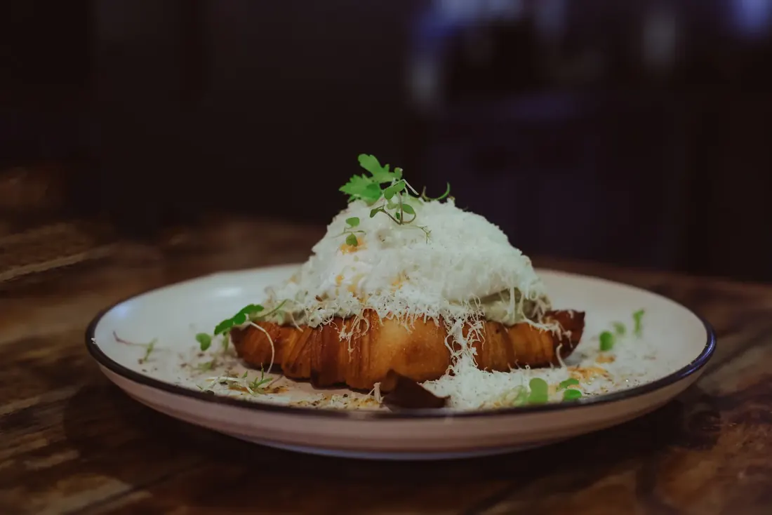 Avo Smash — house croissant with avocado, Danish feta, poached eggs and shaved haloumi
