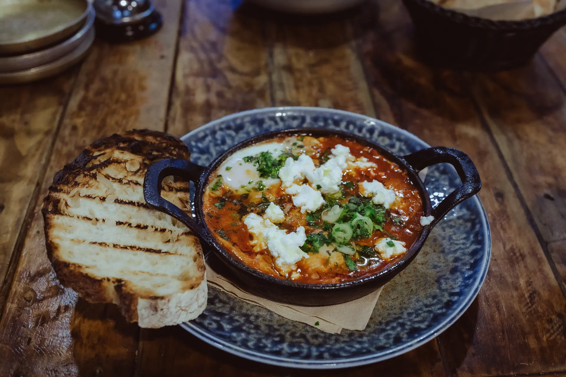 Doctor Shakshuka — tomato ragout with a baked egg and Danish fetta in a cast iron pan, with grilled sourdough